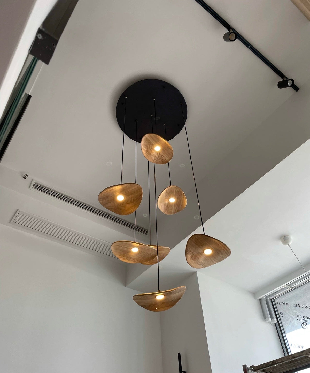Wellenförmige Pendelleuchte aus Holz mit Blattmotiv